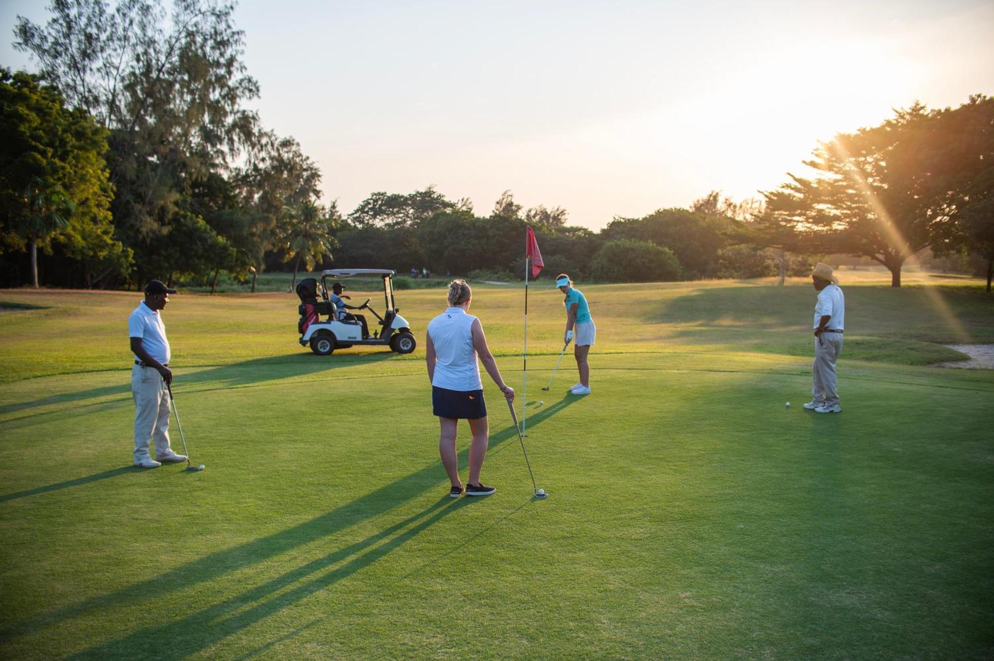 Diamonds Leisure Beach & Golf Resort Diani Beach Esterno foto Golfers putting on the 18th green at the Royal Pines Resort
